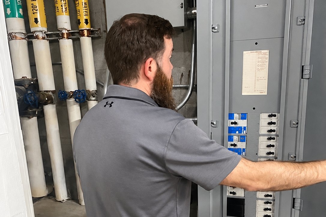 Technician working inside an open commercial breaker panel