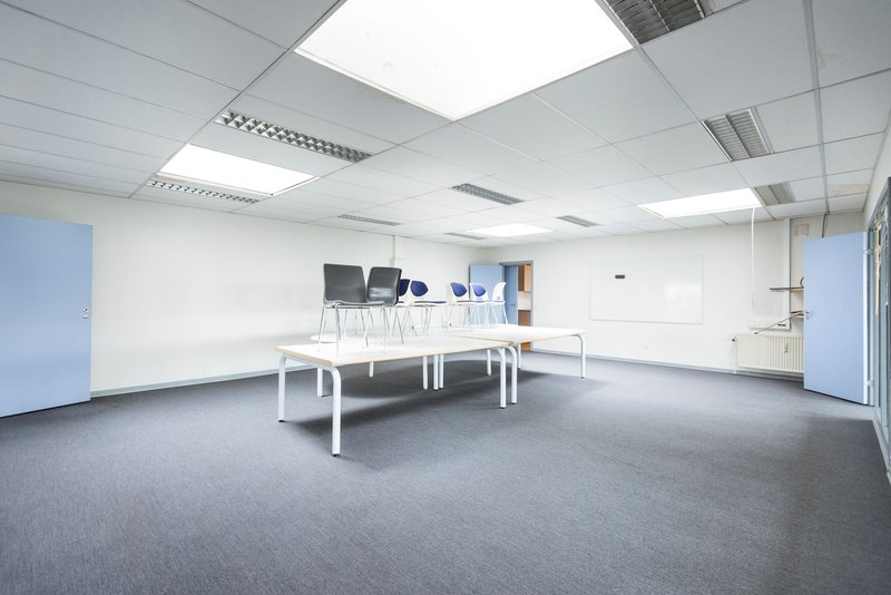 Bright empty meeting room with smooth white walls and recessed lights