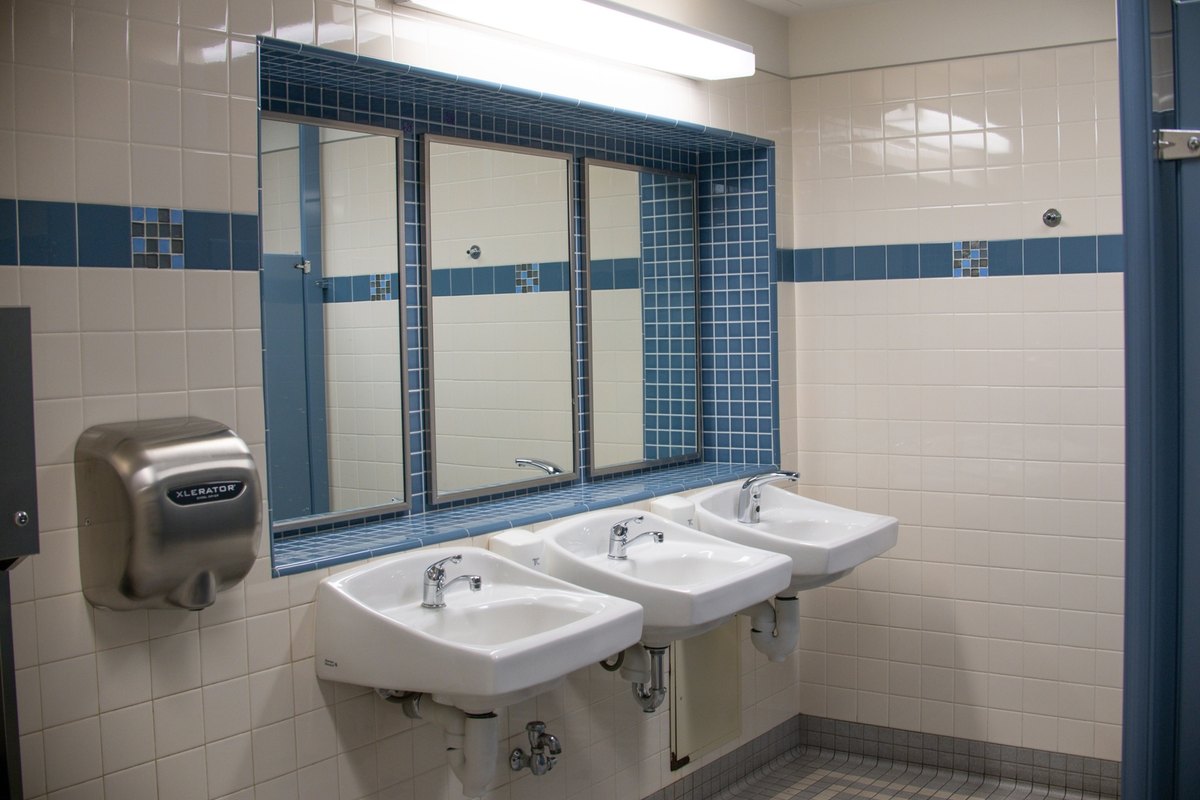 Commercial restroom with three white wall-mounted sinks under a window