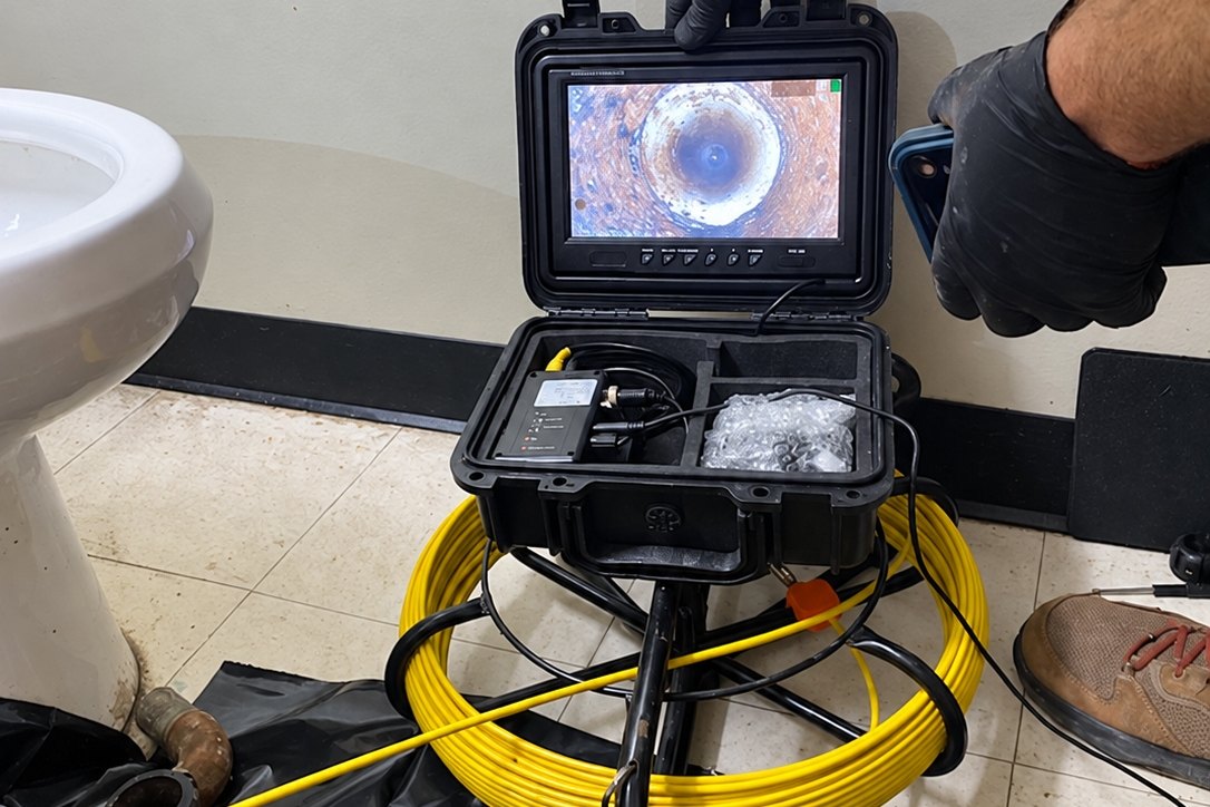 Sewer inspection camera monitor and yellow cable reel set up in a restroom
