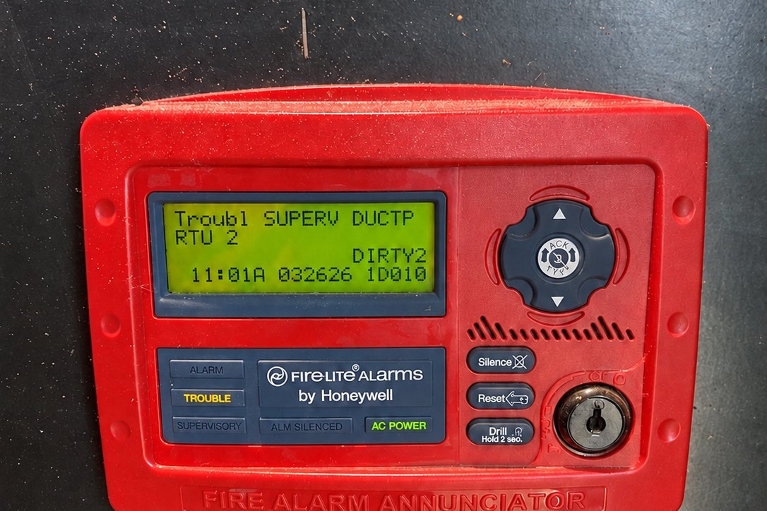 Red fire alarm annunciator panel showing a trouble message