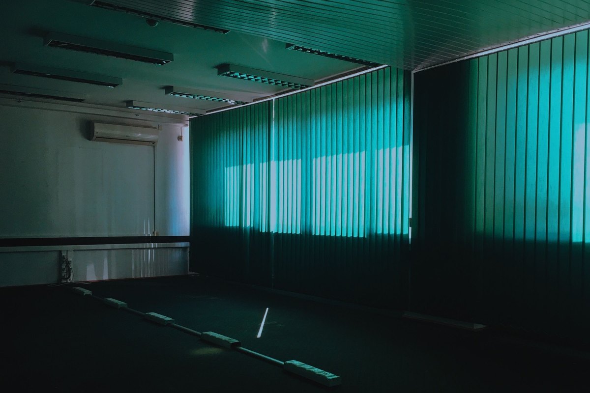Empty office with a suspended ceiling, light panels, and gray carpet