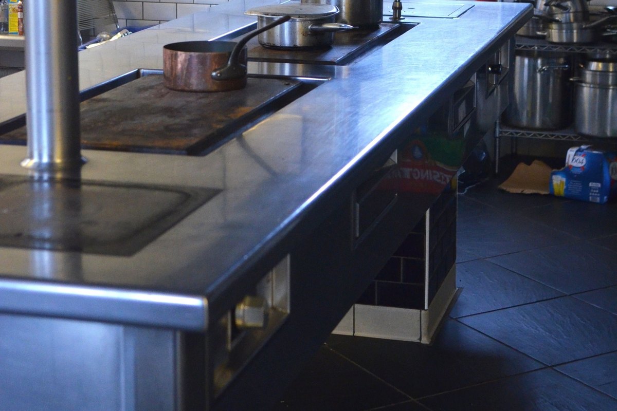 Stainless steel commercial kitchen line with a cooktop and extinguisher